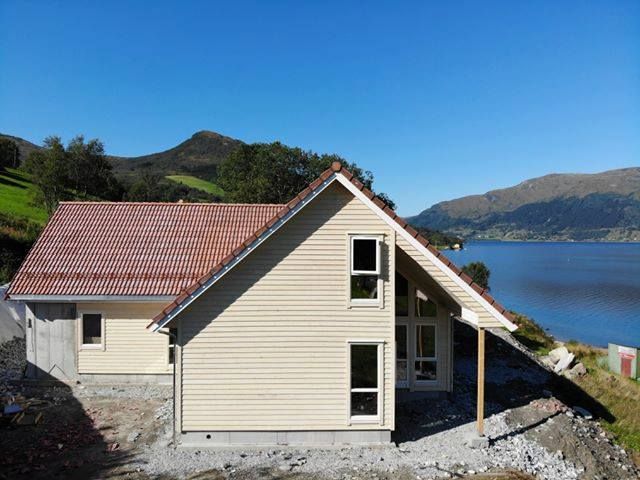 T-forma hus med raudt tak og fjordutsikt